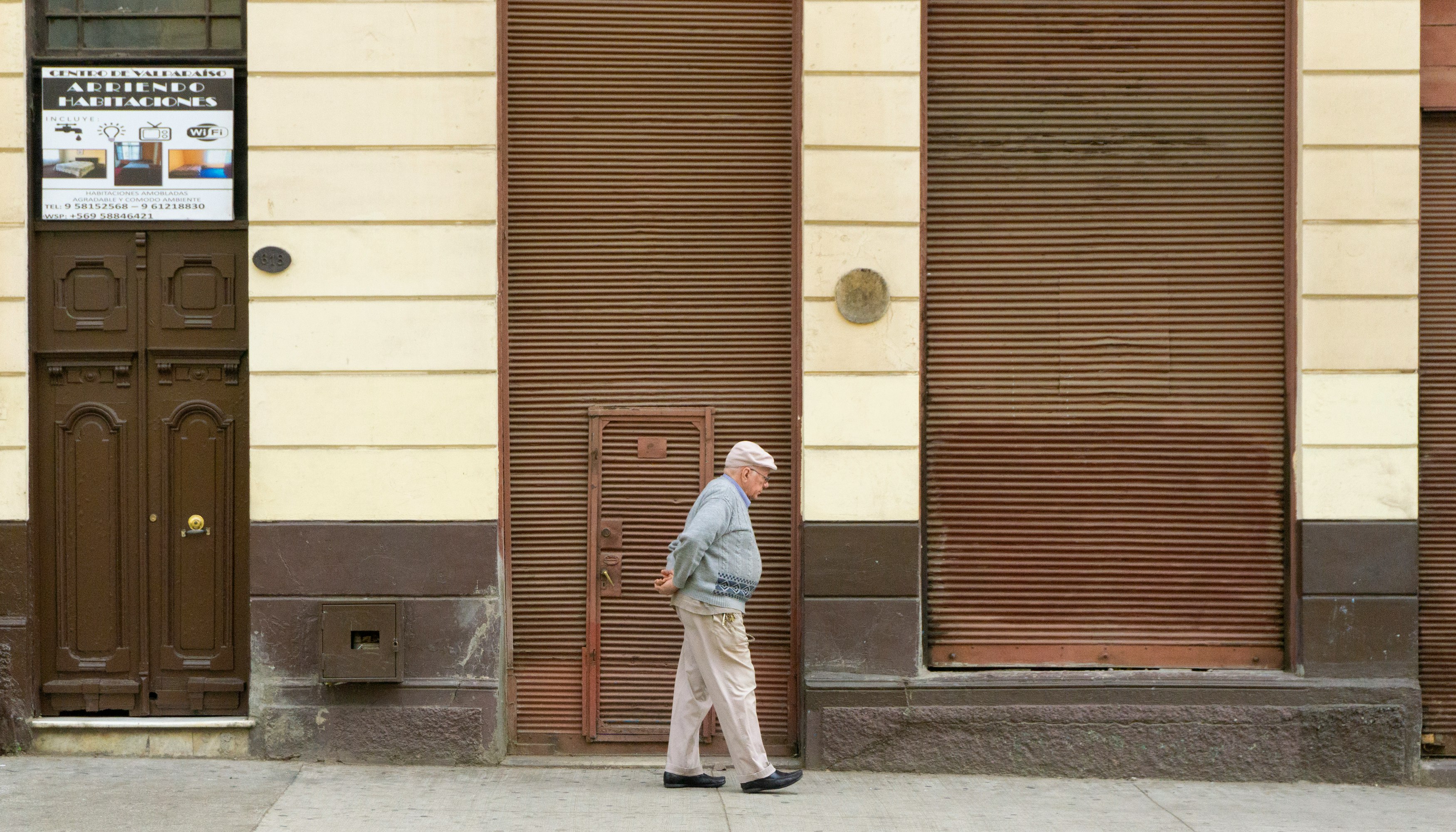 man wearing gray sweater walking on street